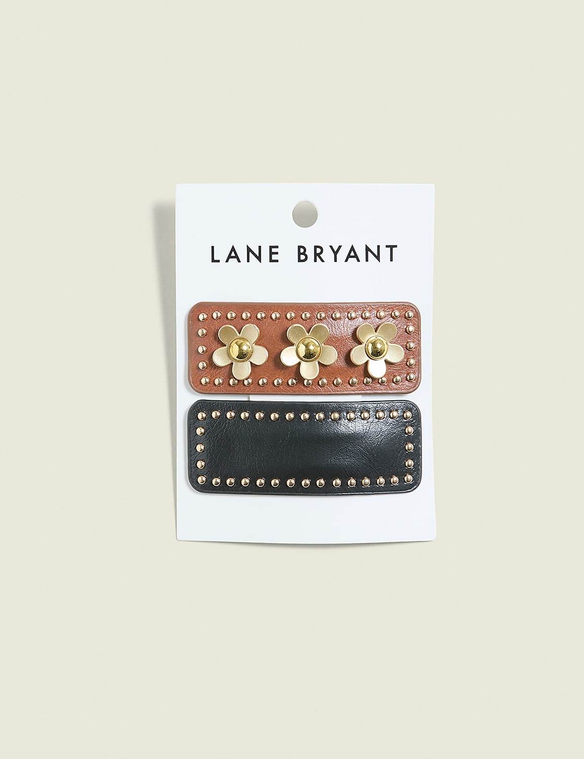 Two decorative hair clips, one brown with gold flowers and the other black with gold studs, are displayed on a white card against a pale gray background. Product Image 1