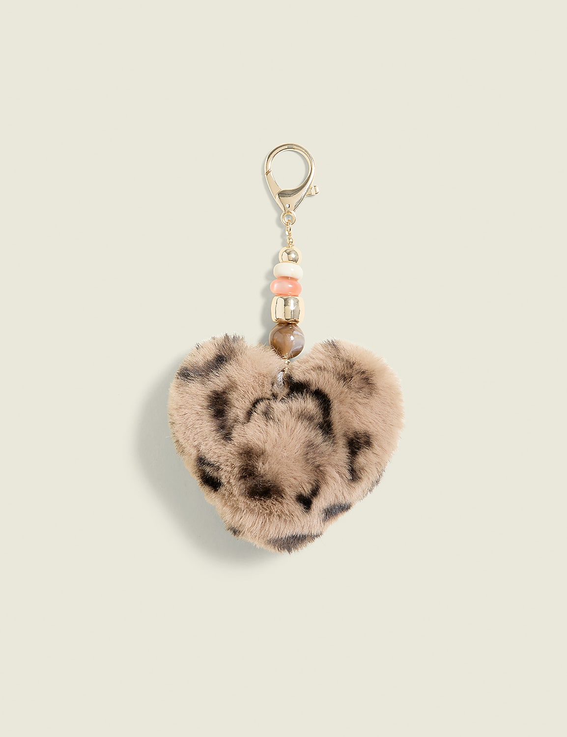 A fuzzy leopard-print heart keychain with beaded accents hangs against a plain, light-colored background. Product Image 1