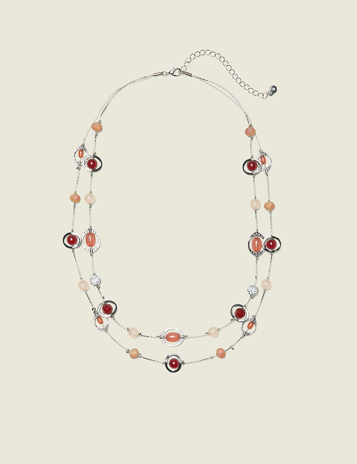 A delicate, multi-strand necklace with coral and clear beads is displayed against a plain, light beige background. Product Image 1