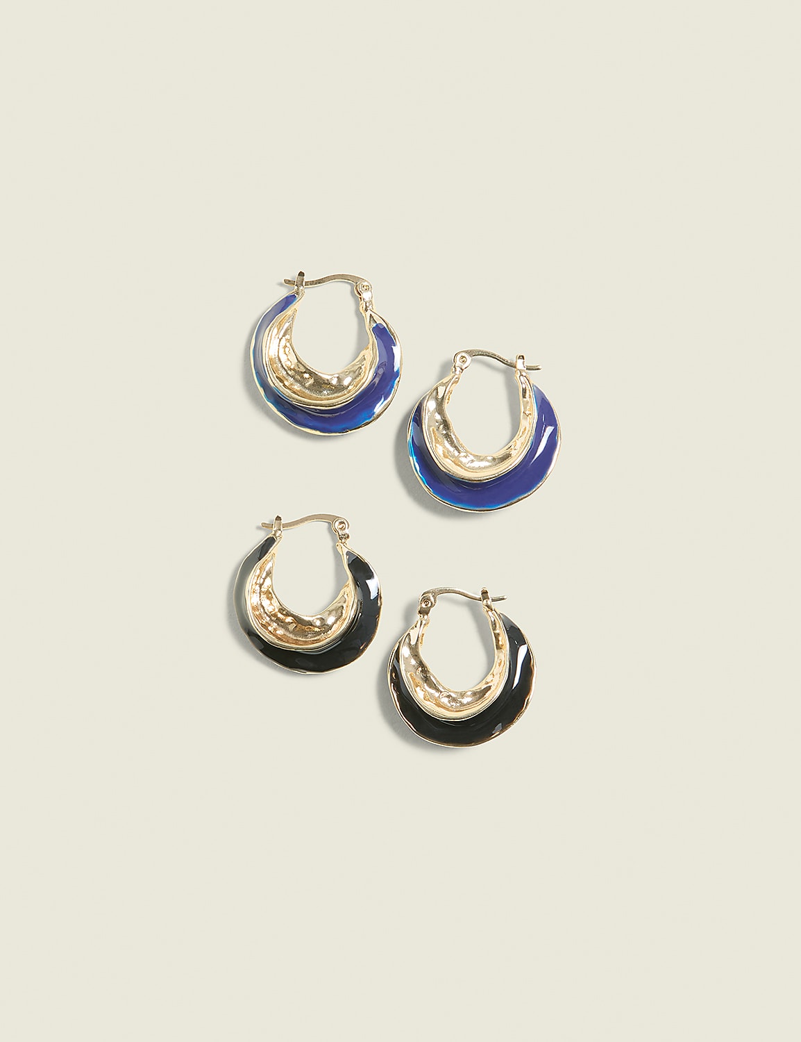 Two pairs of gold hoop earrings, one with blue enamel and the other with black enamel, are arranged on a plain, light beige background. Product Image 1