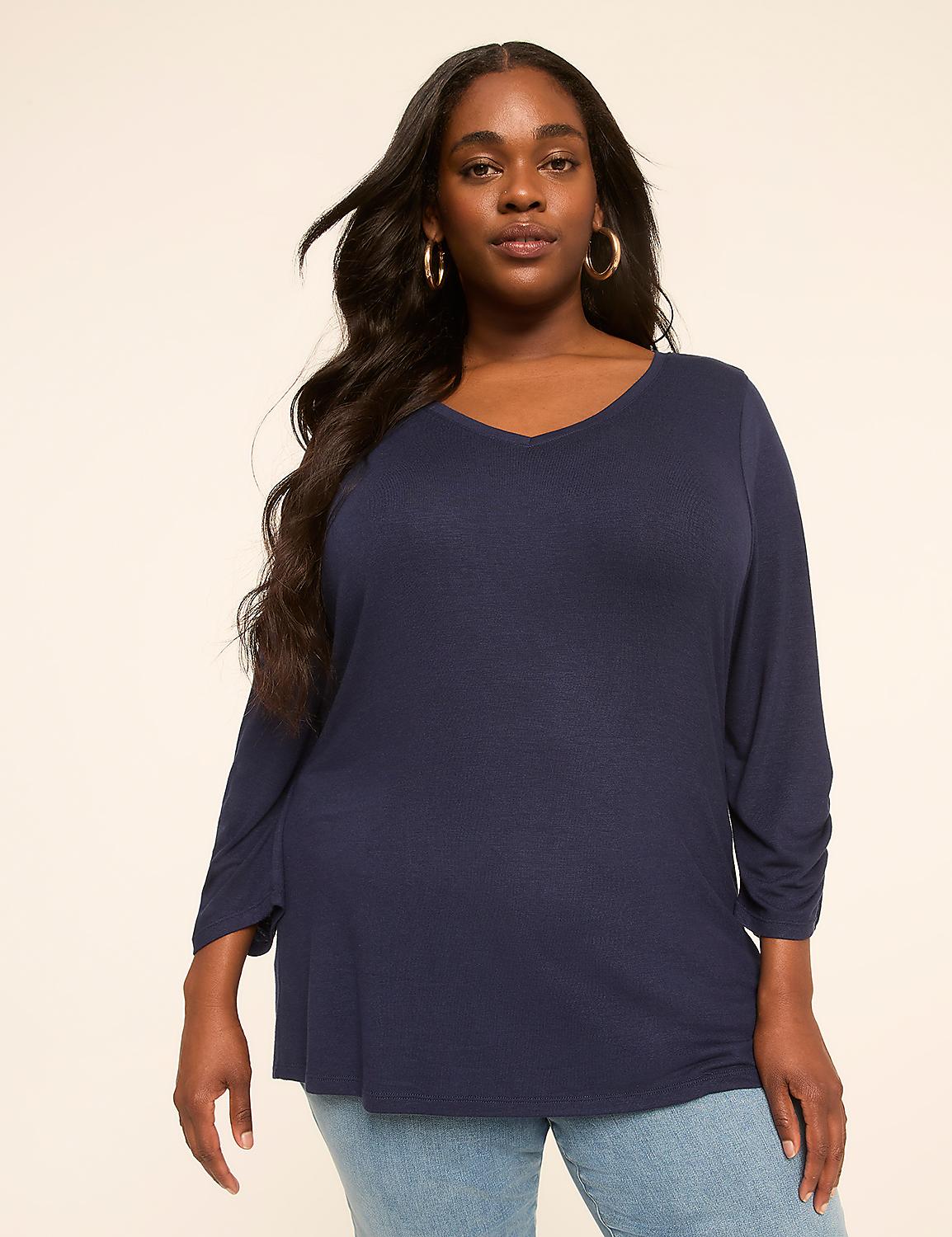 A woman in a navy v-neck shirt and jeans stands against a plain, light-colored background. Product Image 1