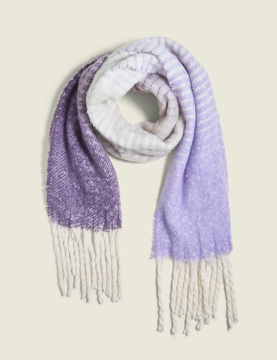A soft, fuzzy scarf with a purple to white gradient and cream-colored fringe lies against a plain, light beige background. Product Image 1