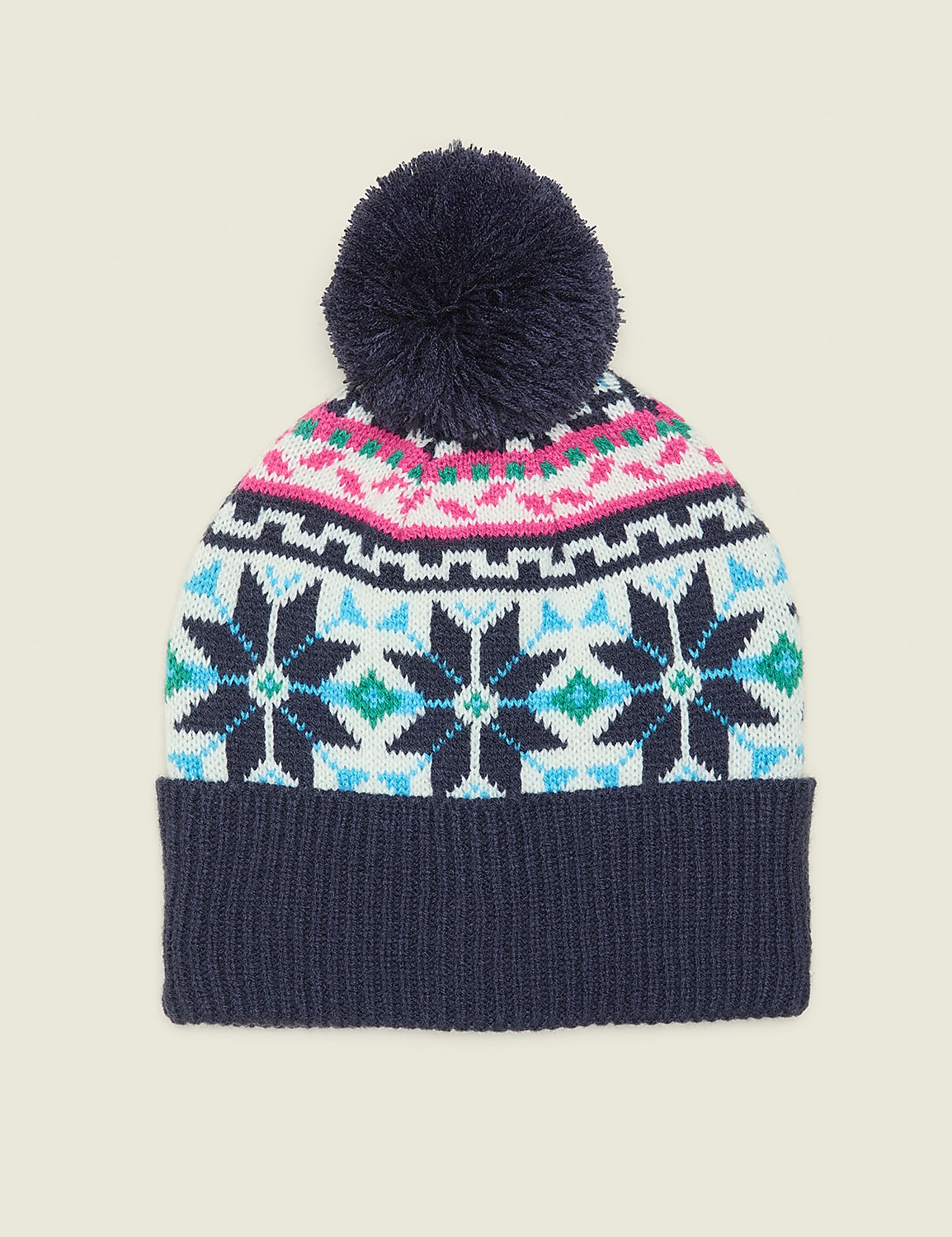 A navy blue pom-pom sits atop a colorful knitted beanie with a fair isle pattern, set against a plain, light beige background. Product Image 1