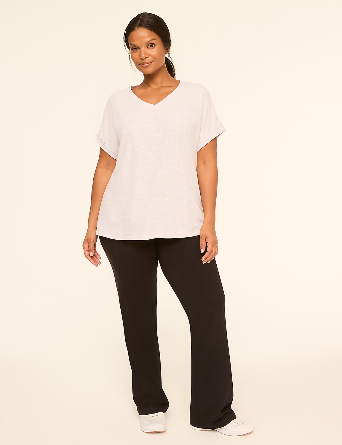 A woman in a light grey v-neck t-shirt and black pants stands against a plain, light-colored background. Product Image 3