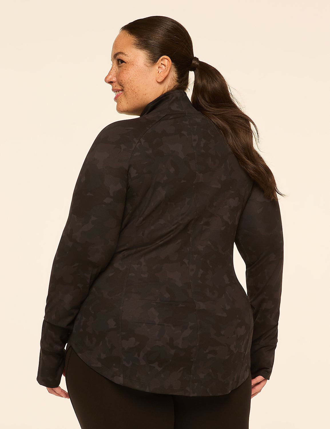 A woman with dark hair pulled into a ponytail wears a black camouflage jacket and black leggings against a plain, light-colored background. Product Image 2