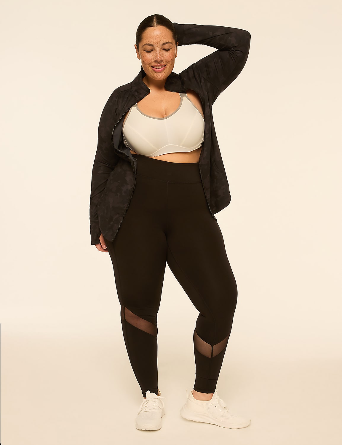 A woman in athletic wear stands against a plain, light-colored background, with her hand raised to her head. Product Image 3