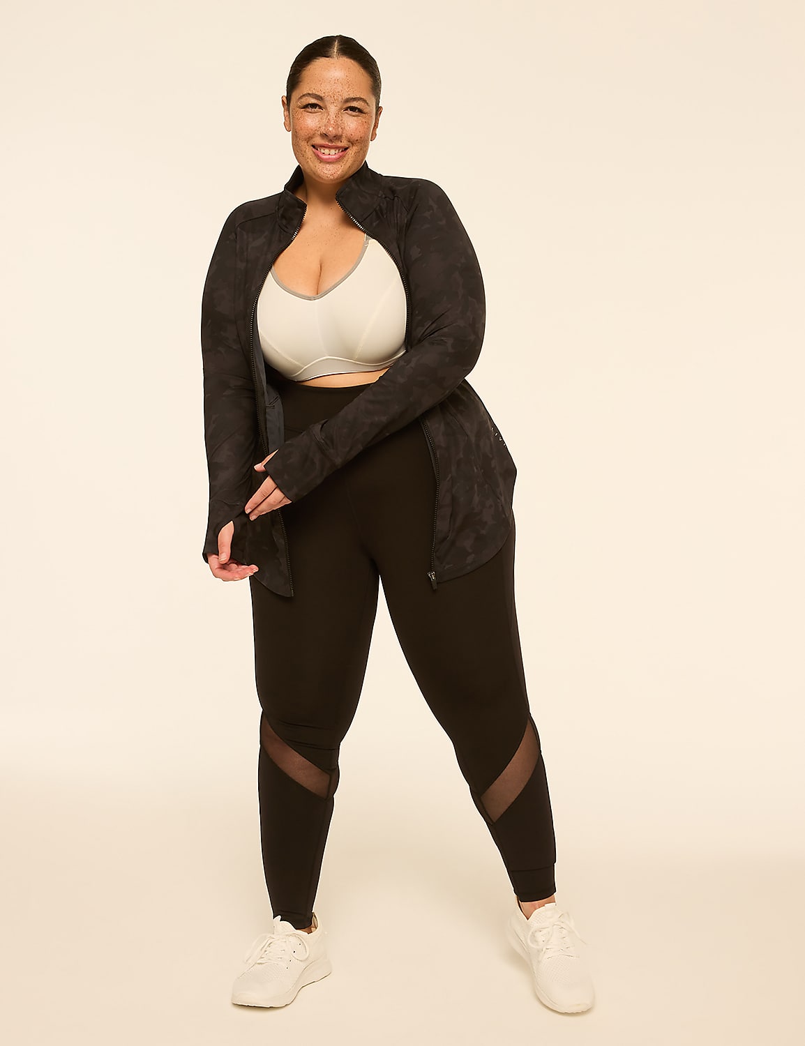 A woman in athletic wear stands against a plain, light-colored background, with her hand raised to her head. Product Image 3