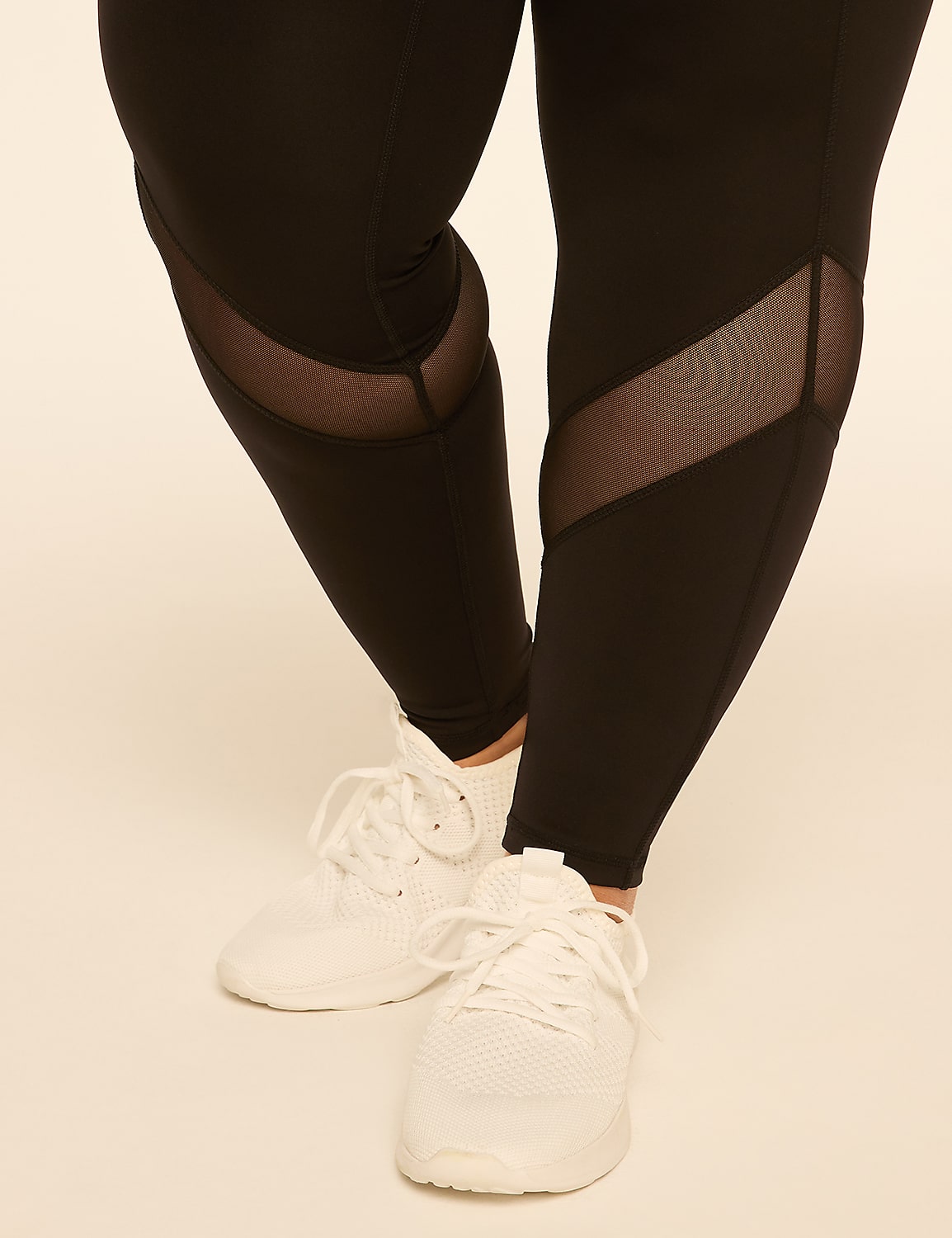 Black leggings with mesh inserts and white sneakers stand out against a plain, light-colored background. Product Image 5