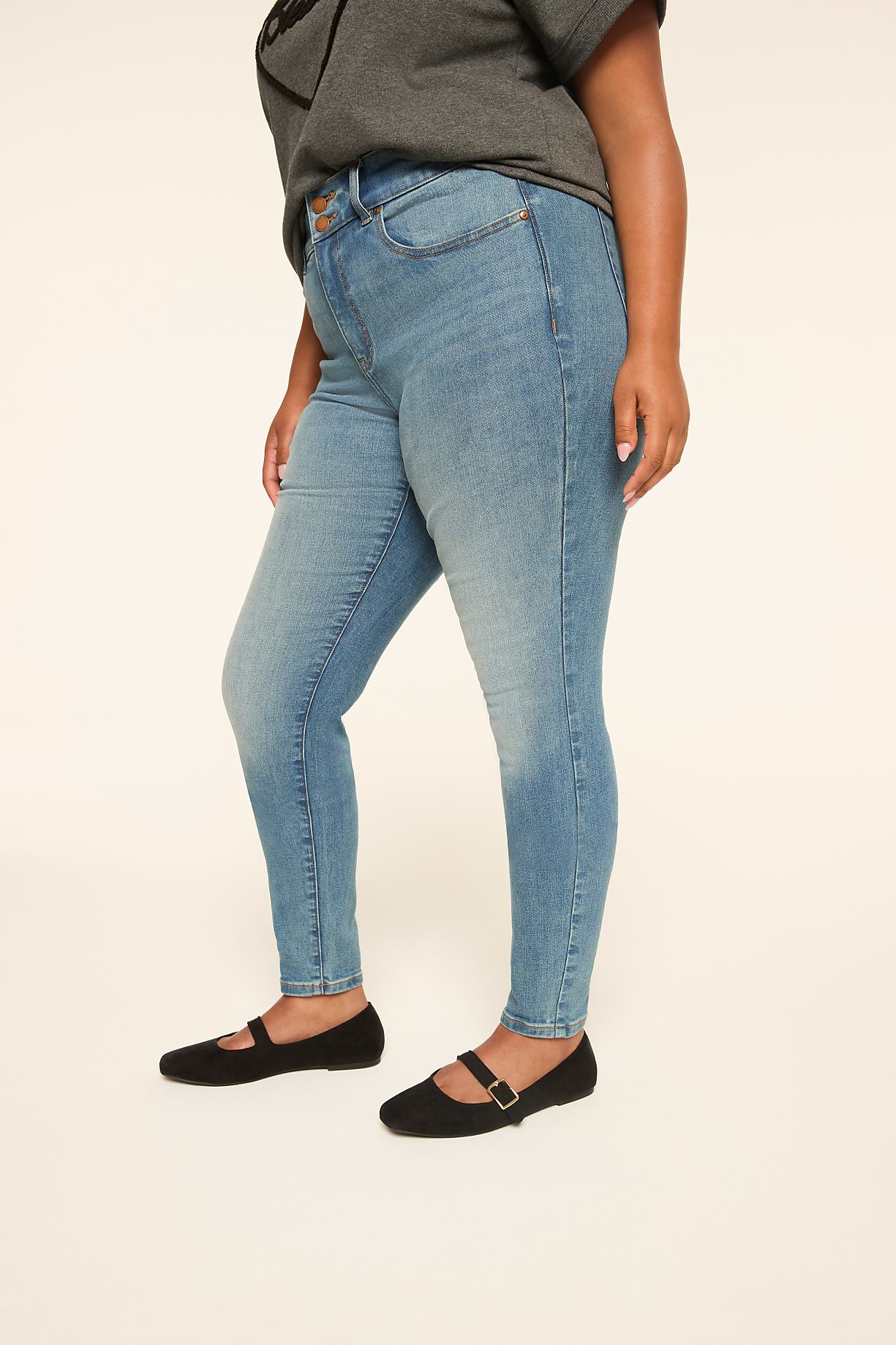 A person in light blue skinny jeans and black flats stands against a plain, light-colored background. Product Image 6