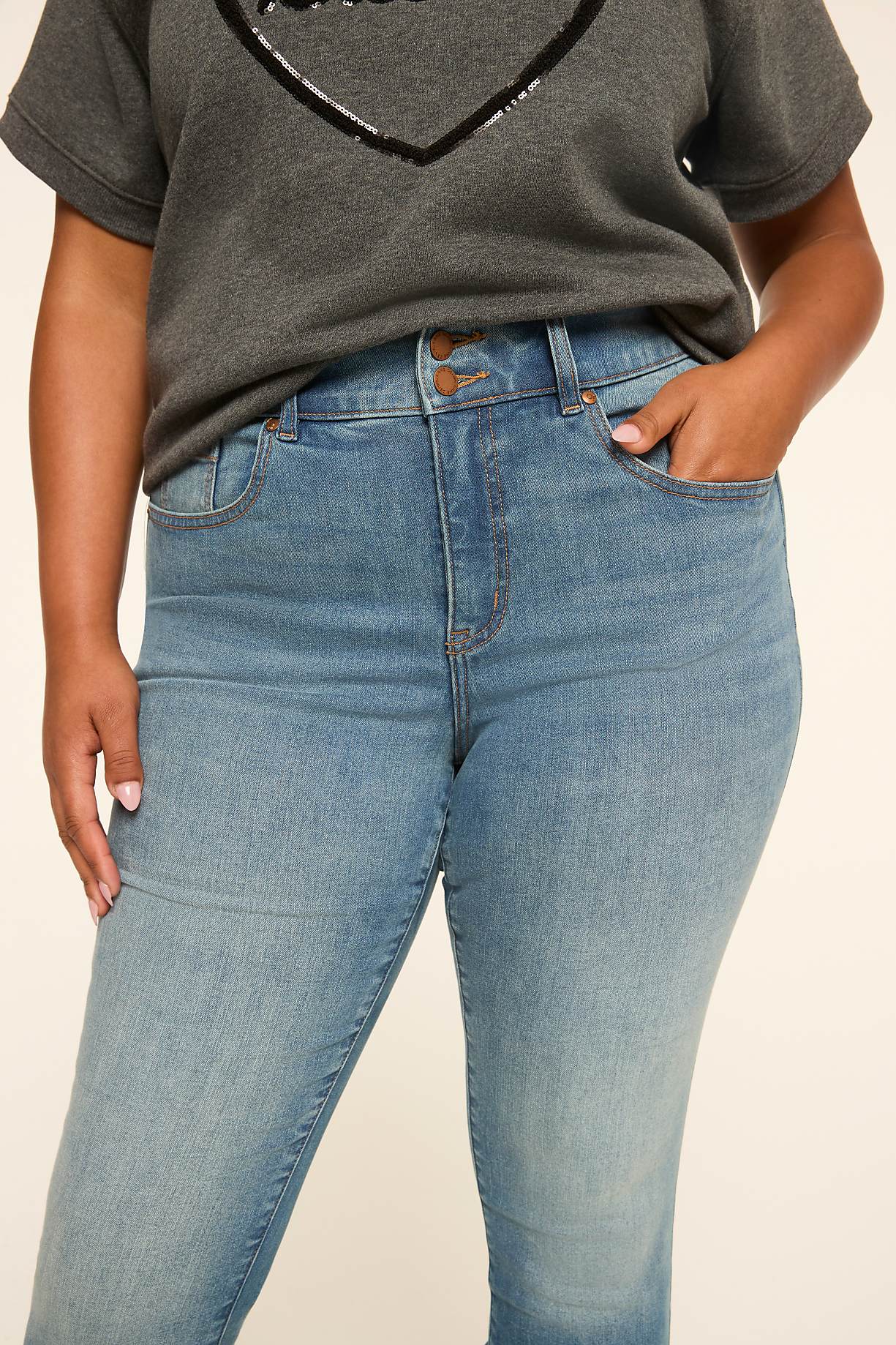 A person in a gray t-shirt with a sequined heart stands in front of a plain background, their hands in the pockets of light-wash jeans. Product Image 7