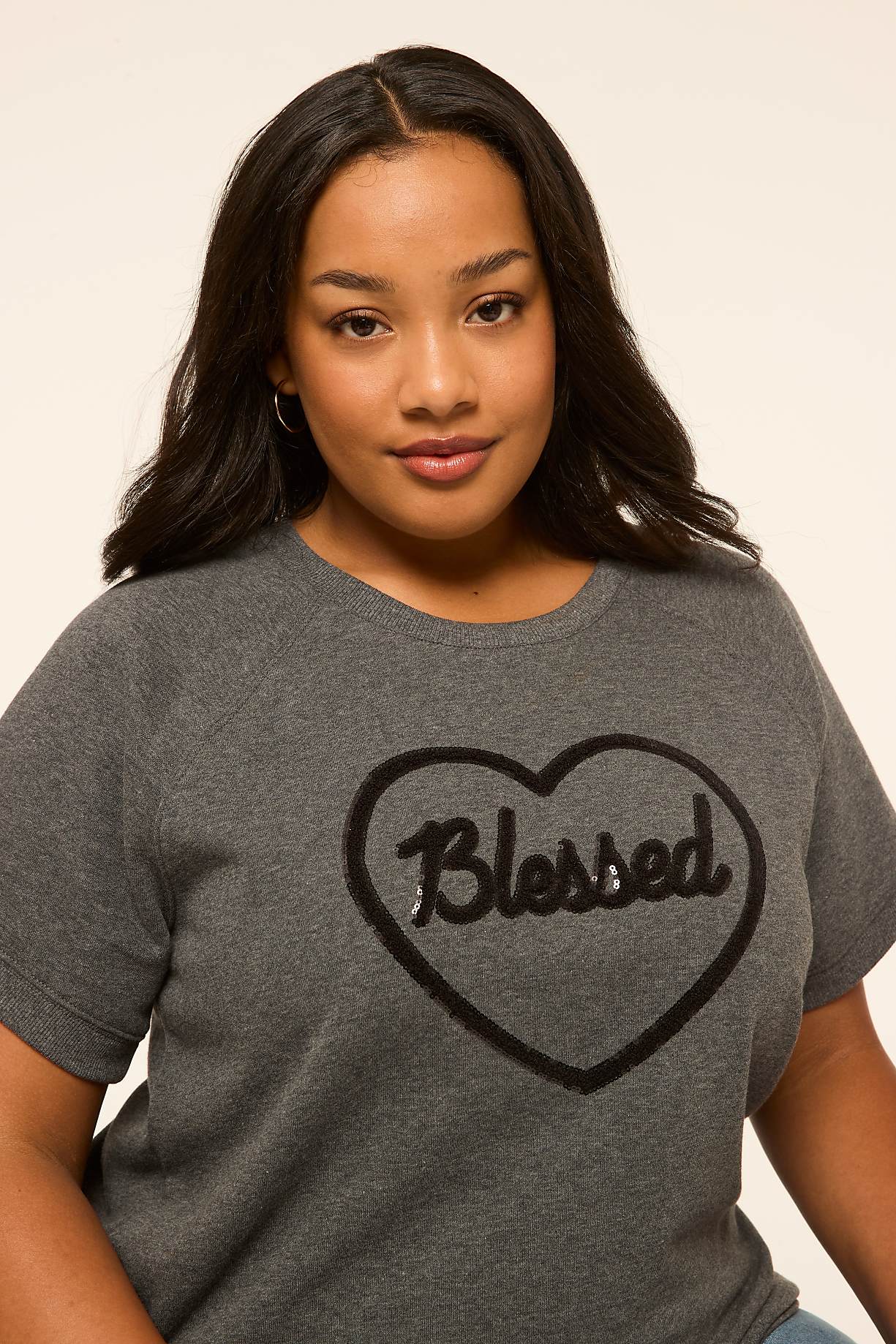 A young woman with dark hair and a gray t-shirt with a heart-shaped "Blessed" graphic is posed against a plain, light-colored background. Product Image 8