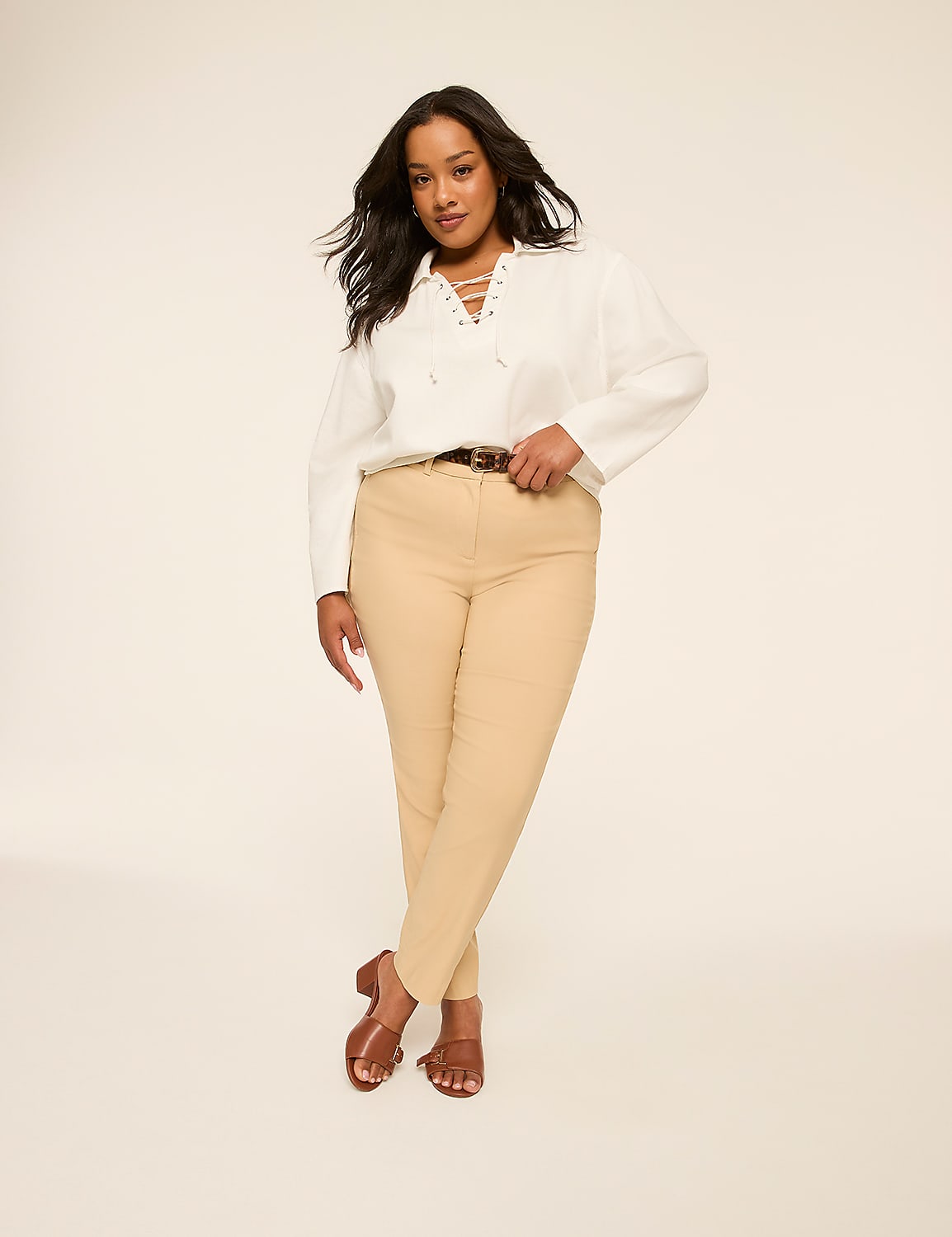 A woman in a white lace-up top and tan pants stands against a plain, light background. Product Image 7