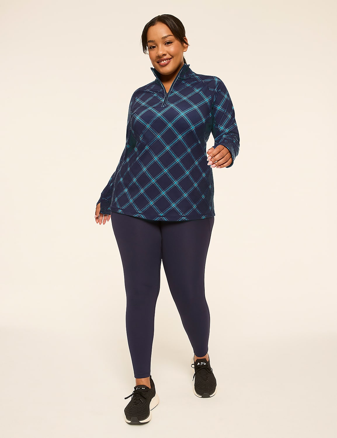 A woman in a plaid quarter-zip shirt and navy leggings stands against a plain, light-colored background. Product Image 3