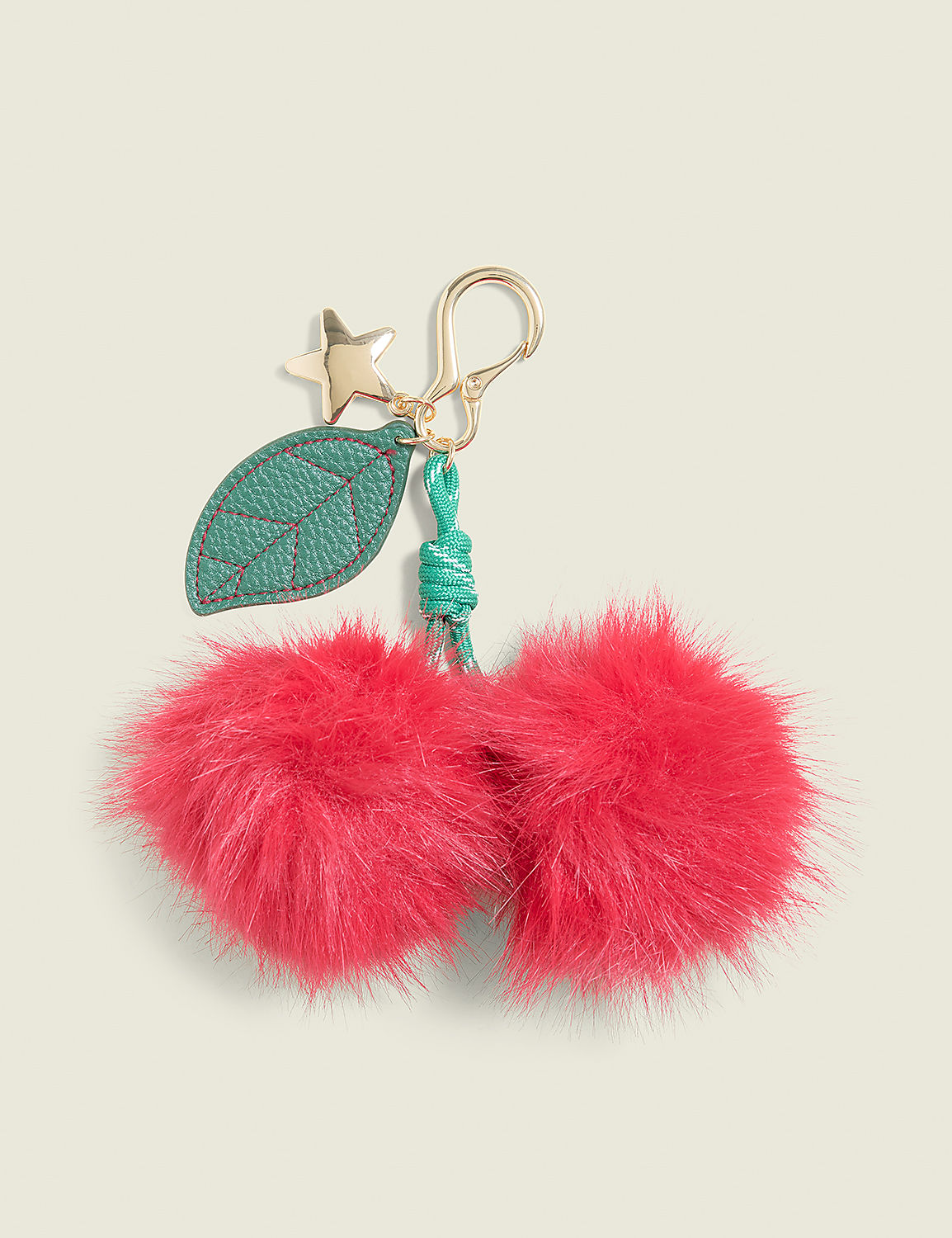 Two fluffy pink pom-poms hang from a gold keychain with a green leaf and star charm against a pale green background. Product Image 1