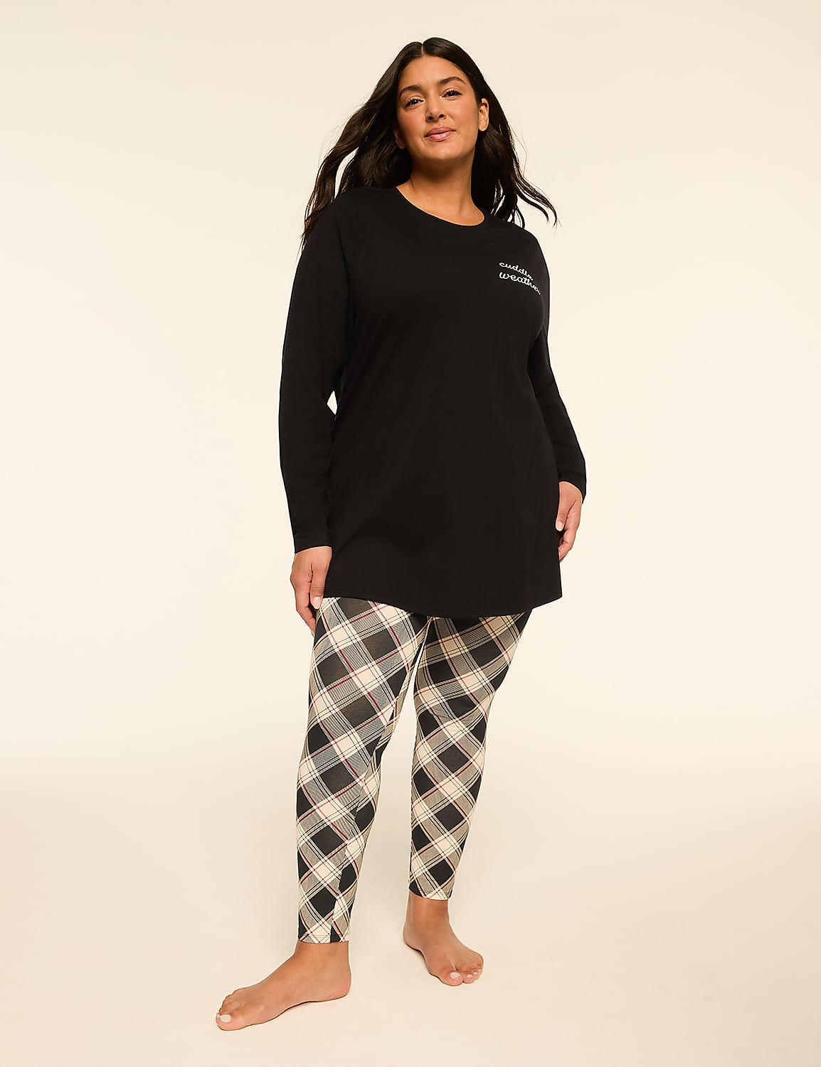 A woman stands in a black long-sleeved top and plaid leggings against a plain, light background. Product Image 1