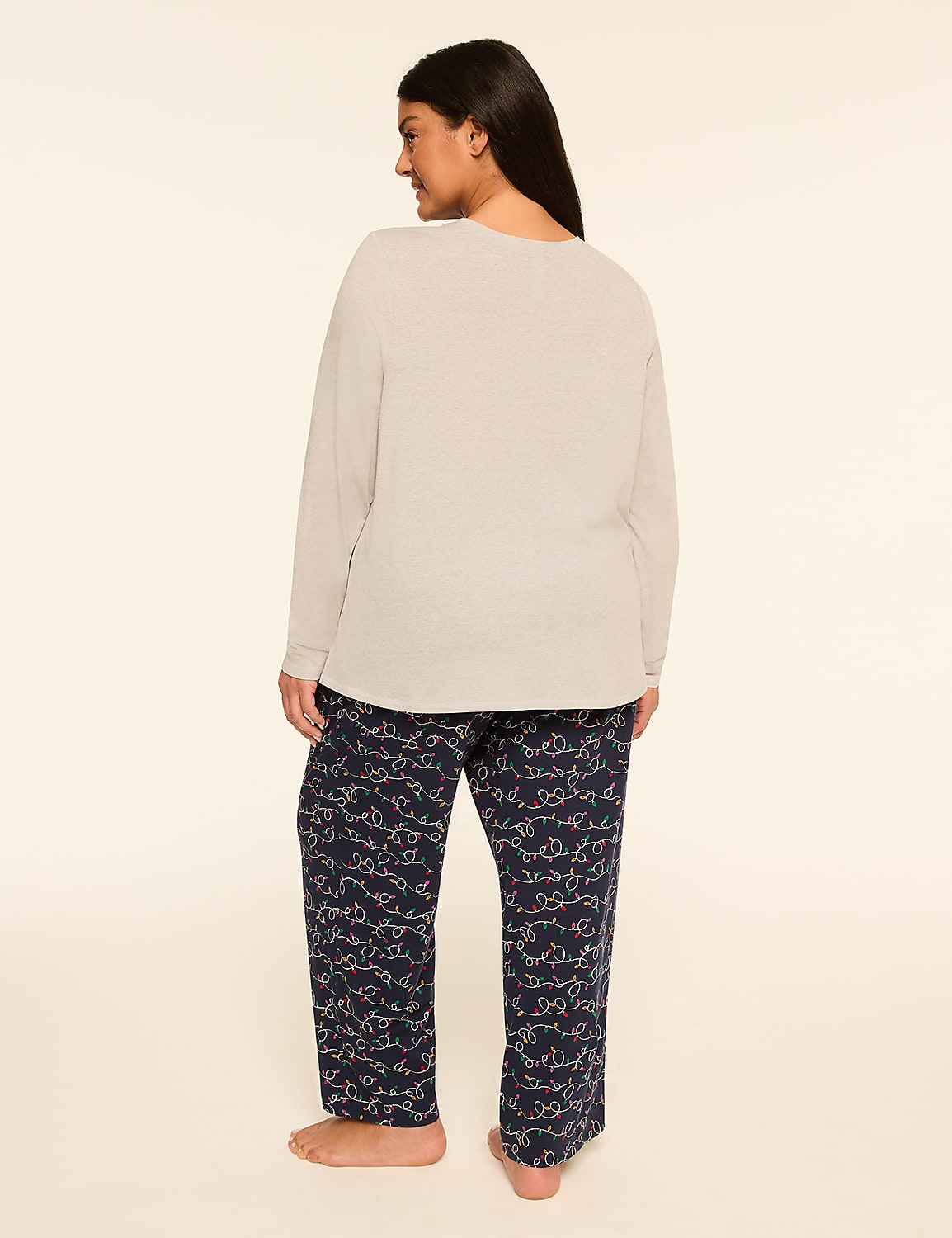 A woman stands facing away from the camera in a light gray long-sleeved shirt and navy blue patterned pajama pants against a plain, light-colored background. Product Image 2