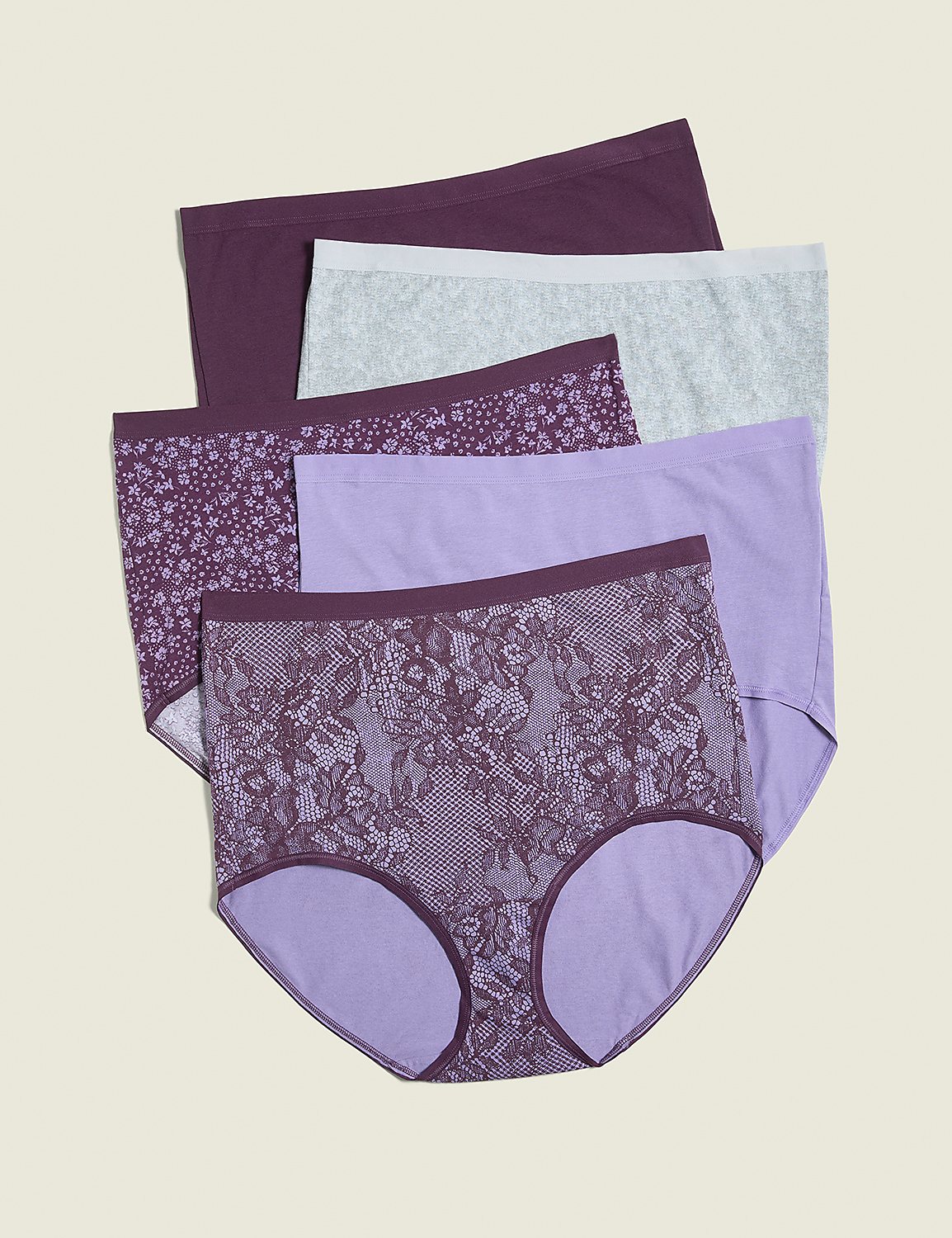 A stack of five pairs of women's underwear in various shades of purple and grey, with floral and lace patterns, are arranged on a plain, light brown background. Product Image 1