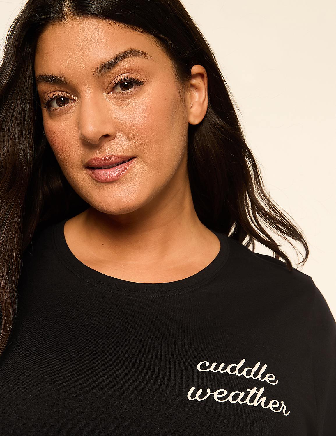 A woman with dark hair and a warm smile wears a black t-shirt with "cuddle weather" embroidered on it, set against a plain, light-colored background. Product Image 4