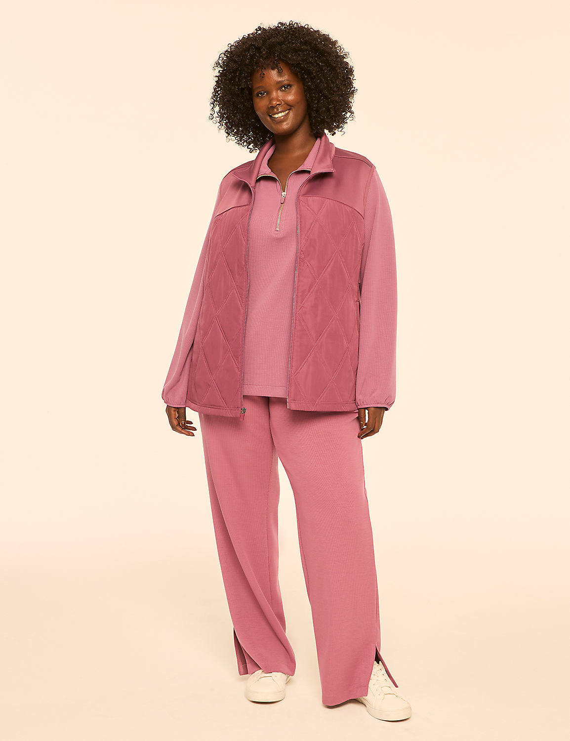 A smiling woman in a mauve tracksuit stands against a plain, light beige background. Product Image 3