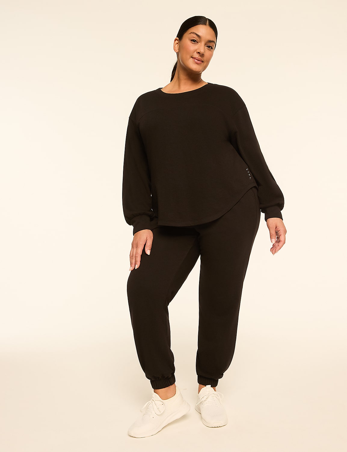 A woman in a black loungewear set stands against a plain, light-colored background. Product Image 3