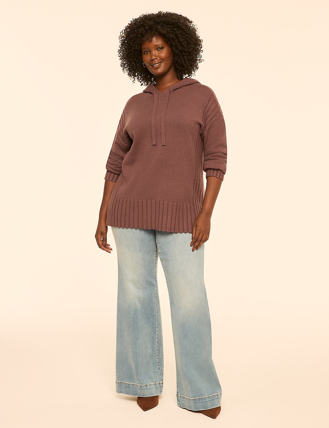 A woman in a mauve hooded sweater and light-wash flared jeans stands against a plain, light beige background. Product Image 3