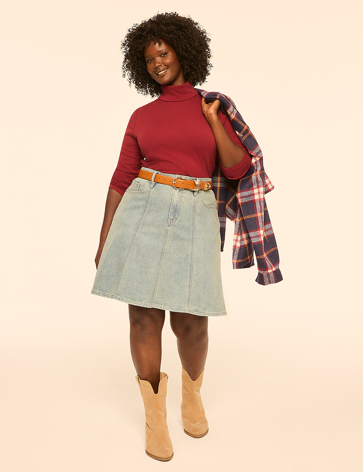 A woman in a maroon turtleneck, denim skirt, and tan boots stands against a plain, light-colored background, with a plaid jacket draped over her shoulder. Product Image 3