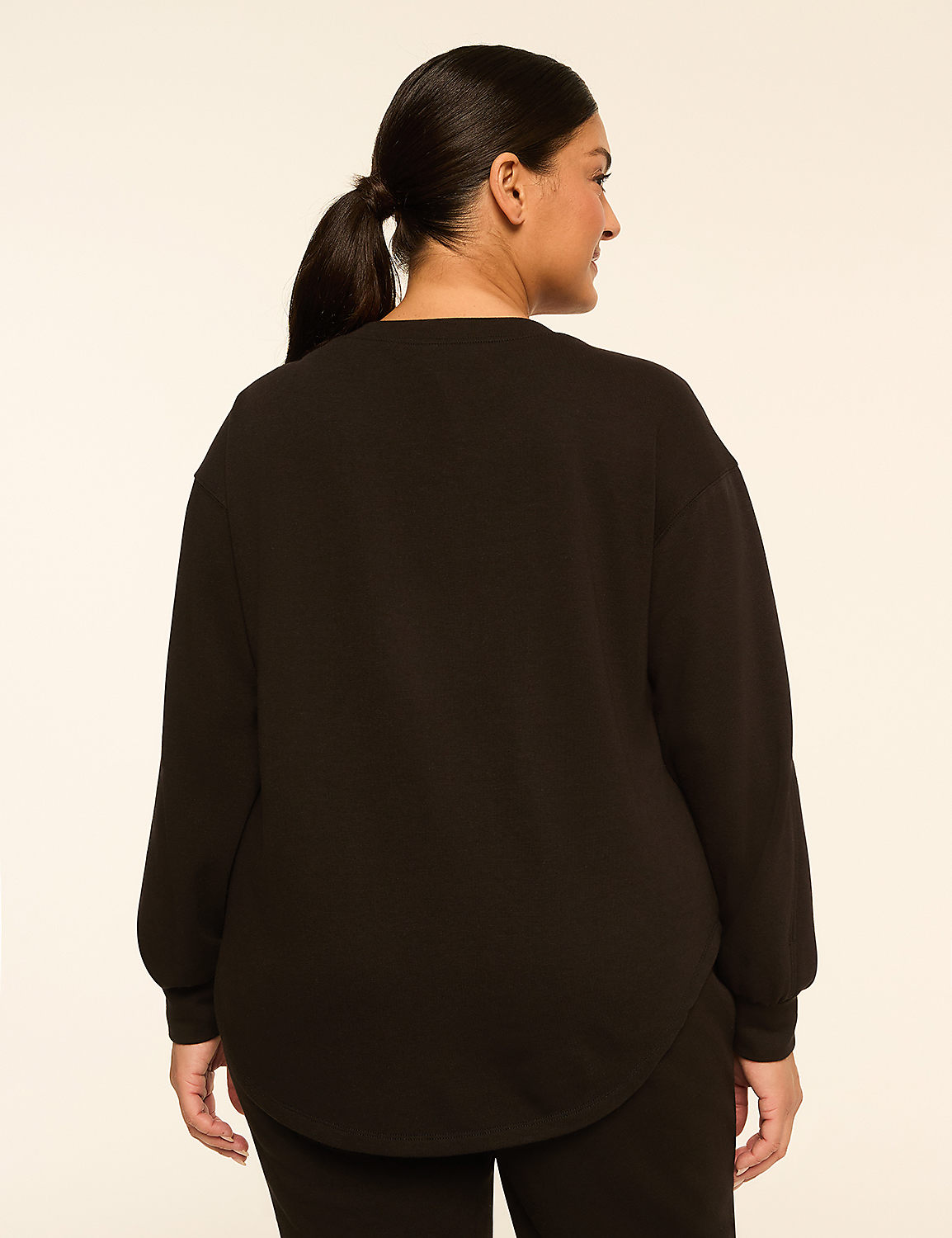 A woman in a black sweatshirt stands against a plain, light-colored background. Product Image 2
