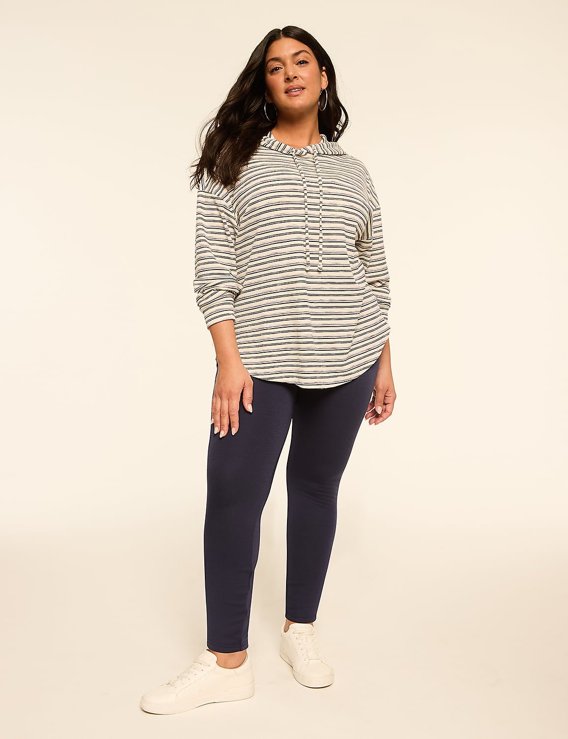 A woman in a striped hoodie and navy leggings stands against a plain, light-colored background. Product Image 3