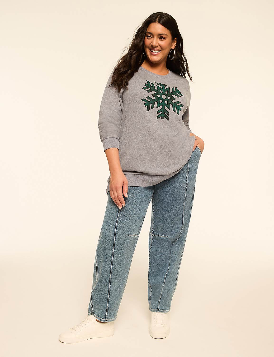 A woman in a gray snowflake sweater and blue jeans stands against a plain, light-colored background. Product Image 3