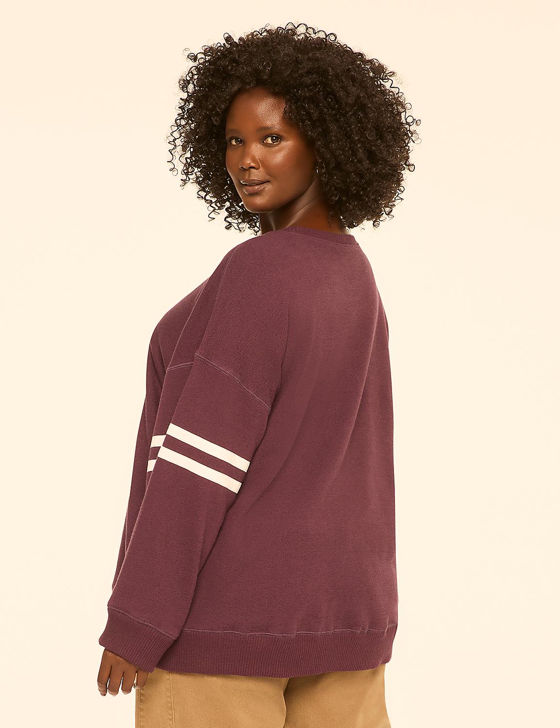 A woman with dark, curly hair poses in a maroon sweatshirt with white stripes on the sleeve, against a plain, light-colored background. Product Image 2
