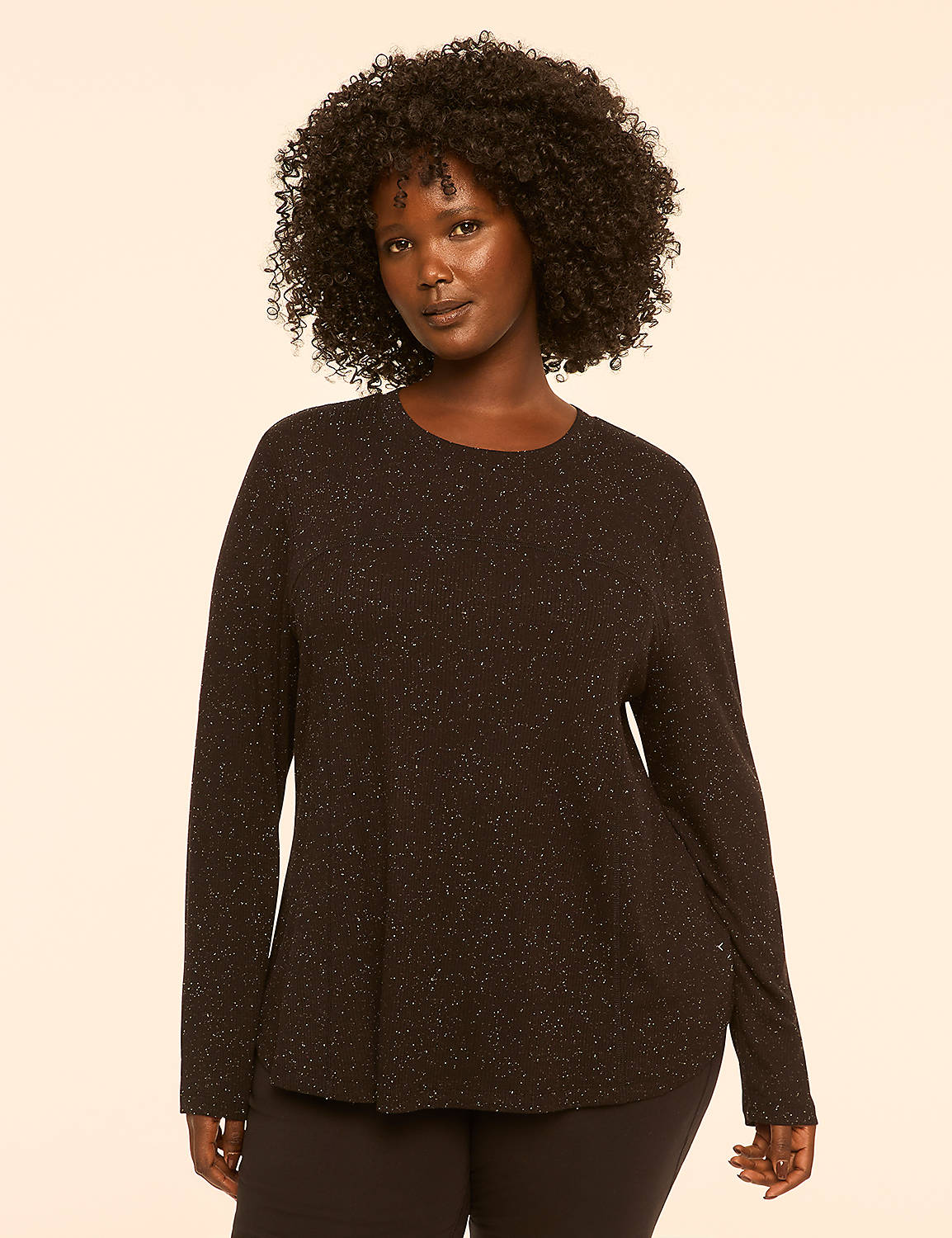 A woman with dark, curly hair and a black, sparkly long-sleeved shirt stands against a plain, light-colored background. Product Image 1