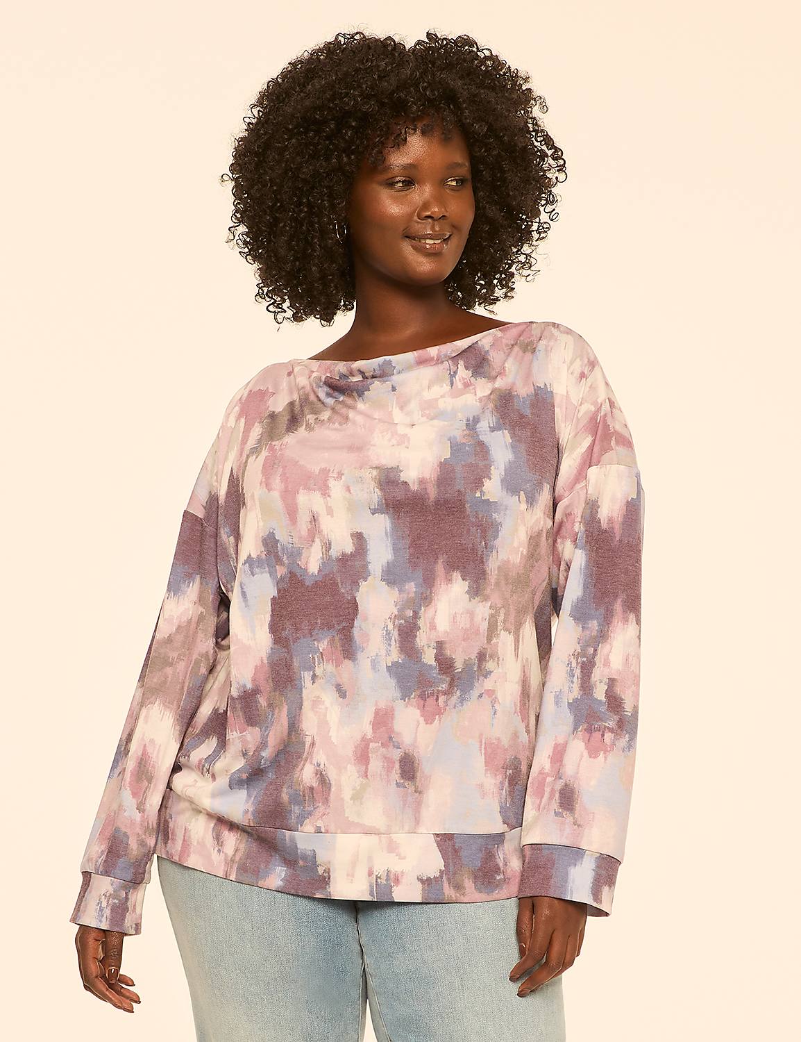 A woman with dark curly hair and a tie-dye sweatshirt stands against a plain, light-colored background. Product Image 1