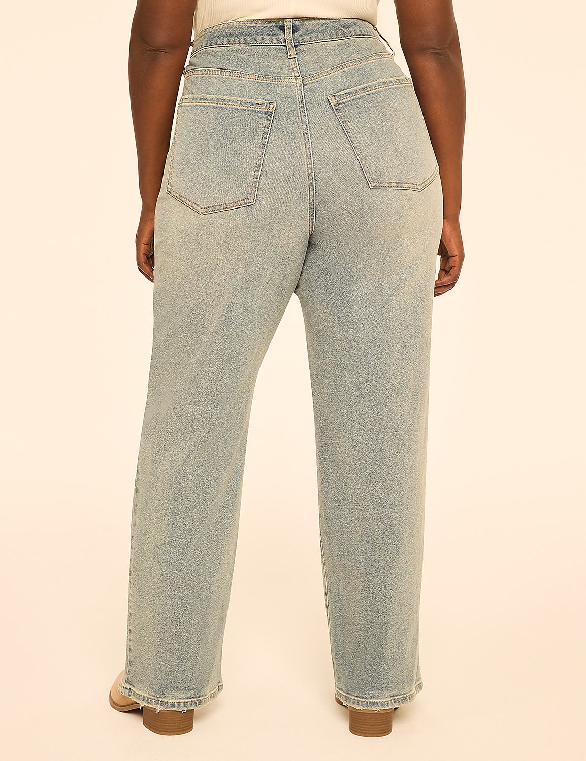 A person wearing light-wash denim jeans stands against a plain, peachy-pink background. Product Image 2