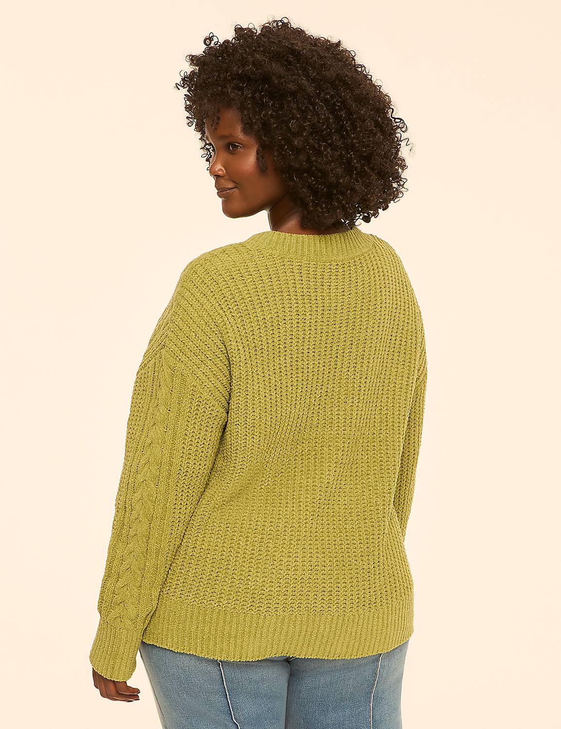 A woman in a green cable-knit sweater and jeans stands against a plain, light-colored background. Product Image 2