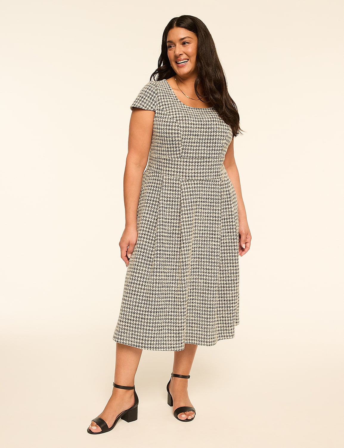 A woman in a checkered dress stands against a plain, light-colored background. Product Image 1