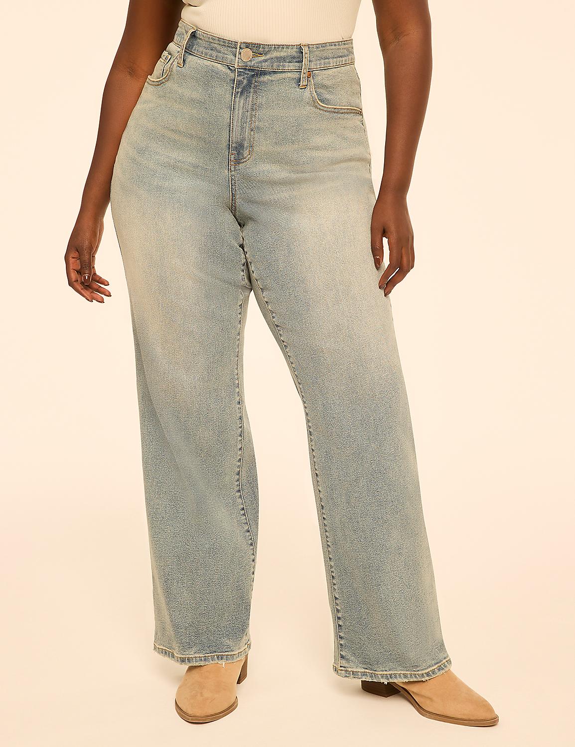 A person wearing light-wash wide-leg jeans and tan boots stands against a plain, peachy-toned background. Product Image 1