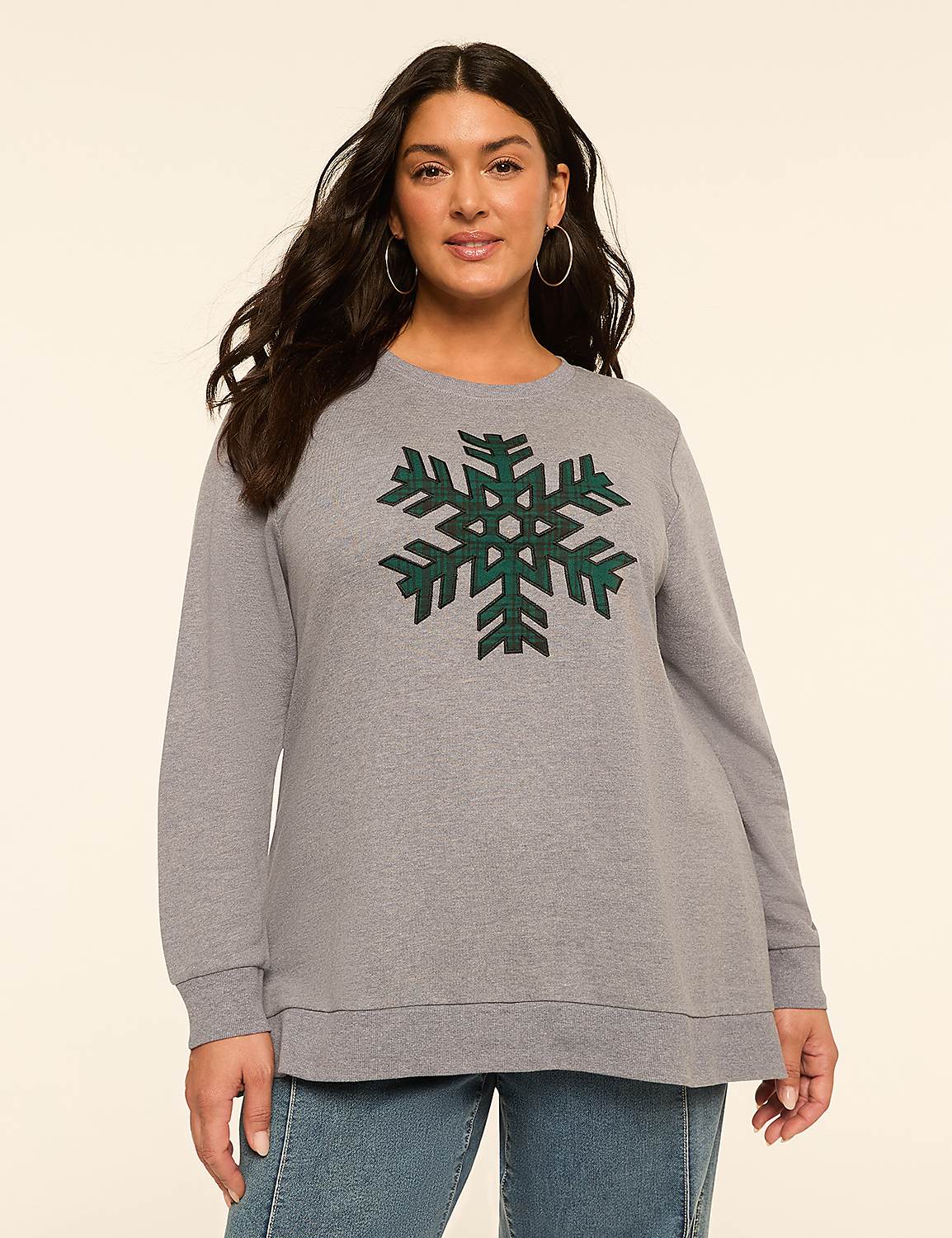 A woman in a gray sweatshirt with a green snowflake design stands against a plain cream background. Product Image 1