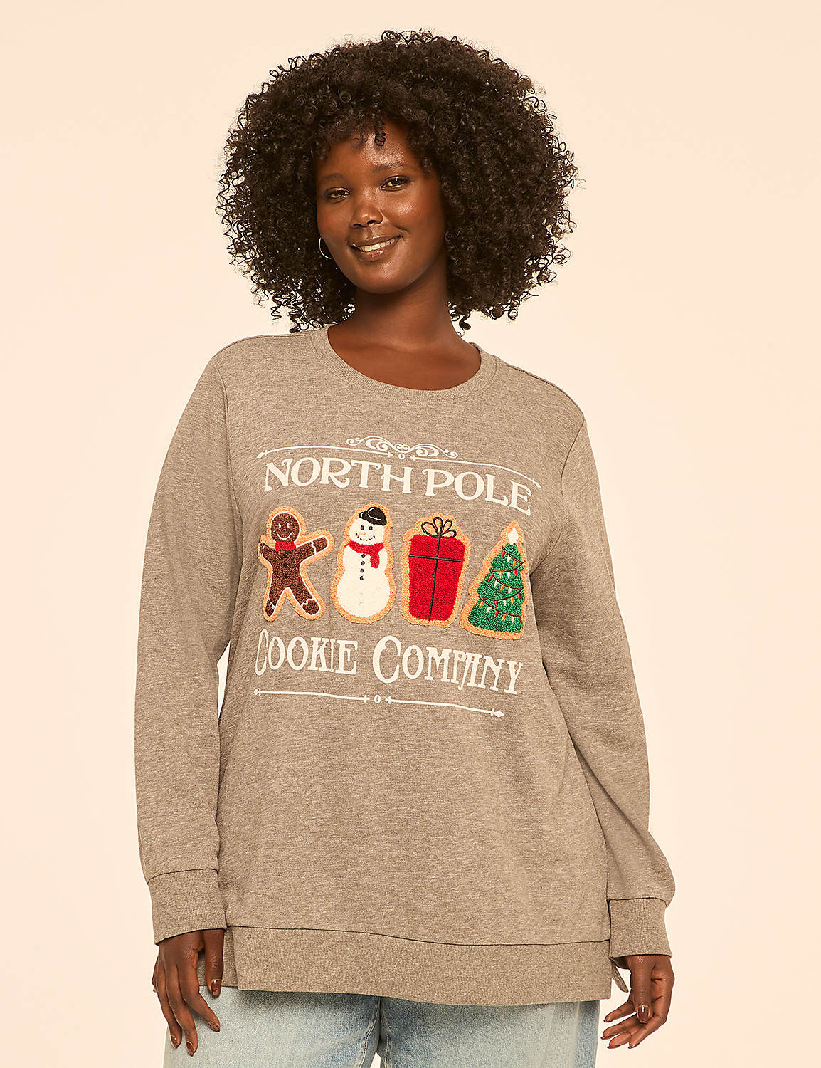 A woman in a gray sweatshirt with a "North Pole Cookie Company" graphic stands against a plain, light-colored background. Product Image 1