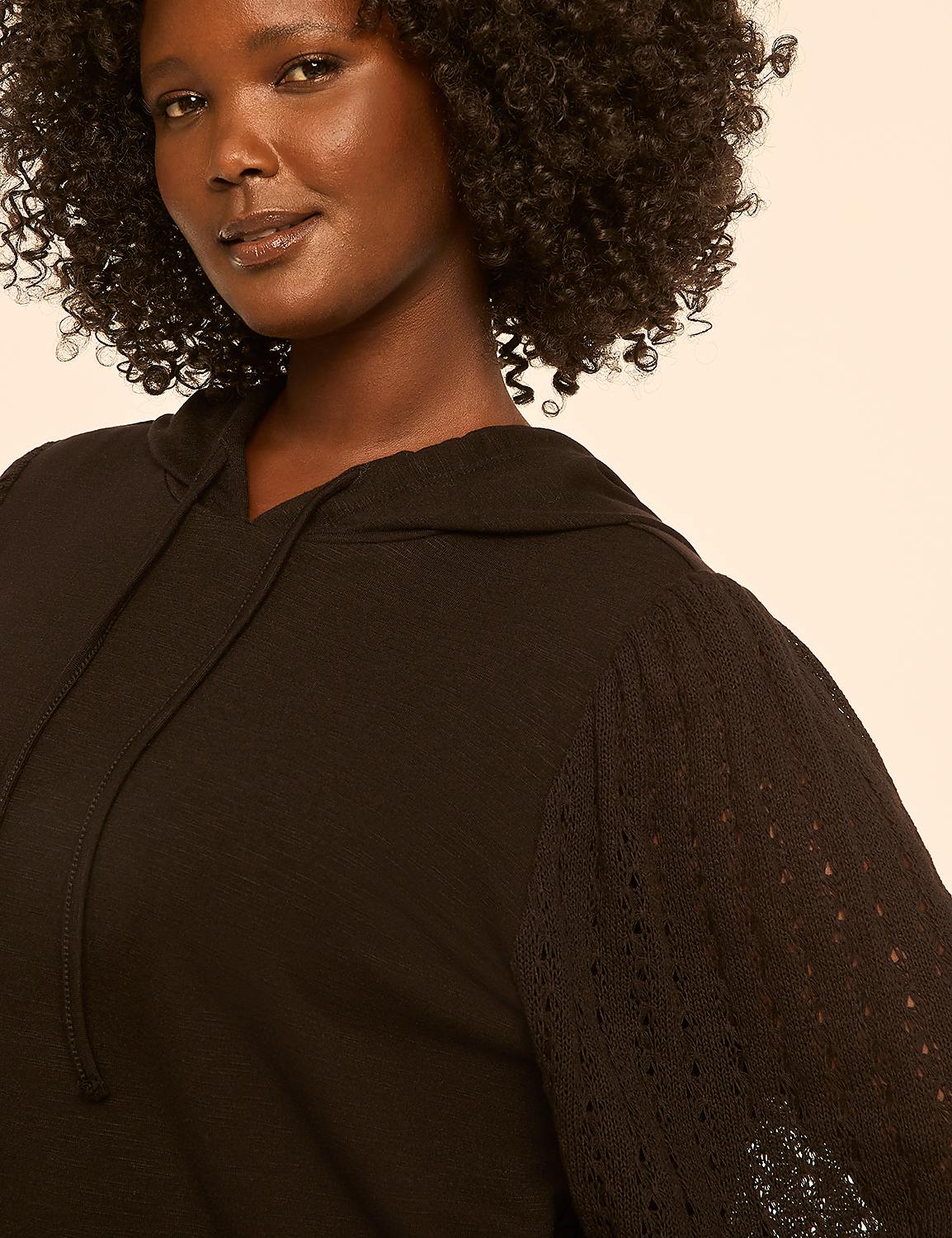 A woman with curly dark hair smiles gently in the foreground, wearing a black hooded top with a textured sleeve, against a plain, light peach background. Product Image 4