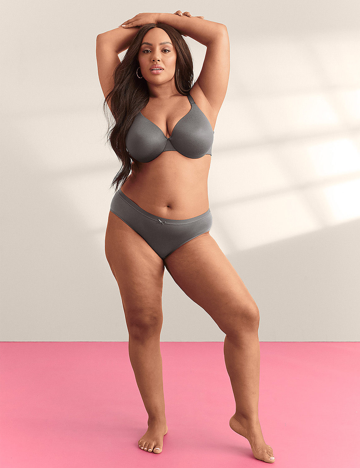 A woman in gray lingerie stands with her arms raised against a plain background with a pink floor. Product Image 5