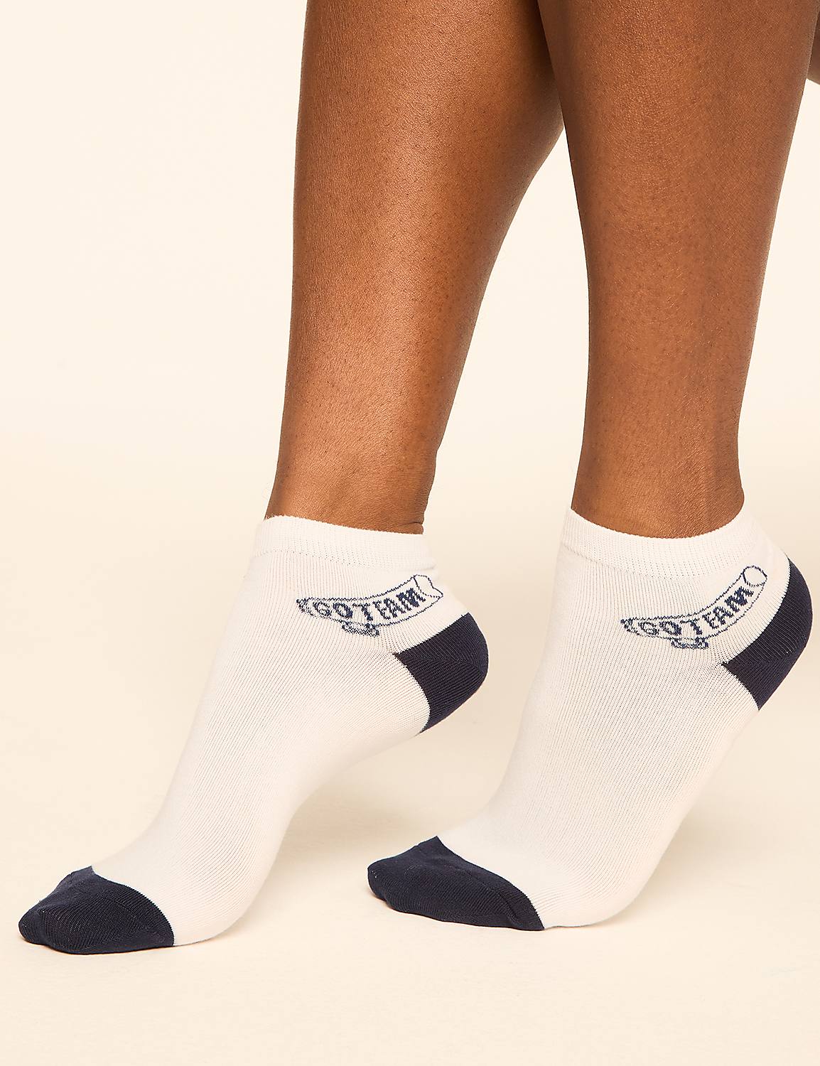White ankle socks with navy blue toe and heel accents and a navy blue banner logo are worn by a person against a plain, light-colored background. Product Image 3