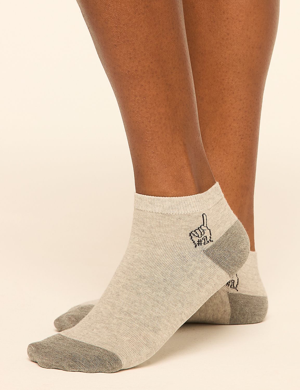Light gray ankle socks with a dark gray toe and heel, featuring a small black graphic of a hand with one finger raised, are worn on a person's legs against a plain, light background. Product Image 1