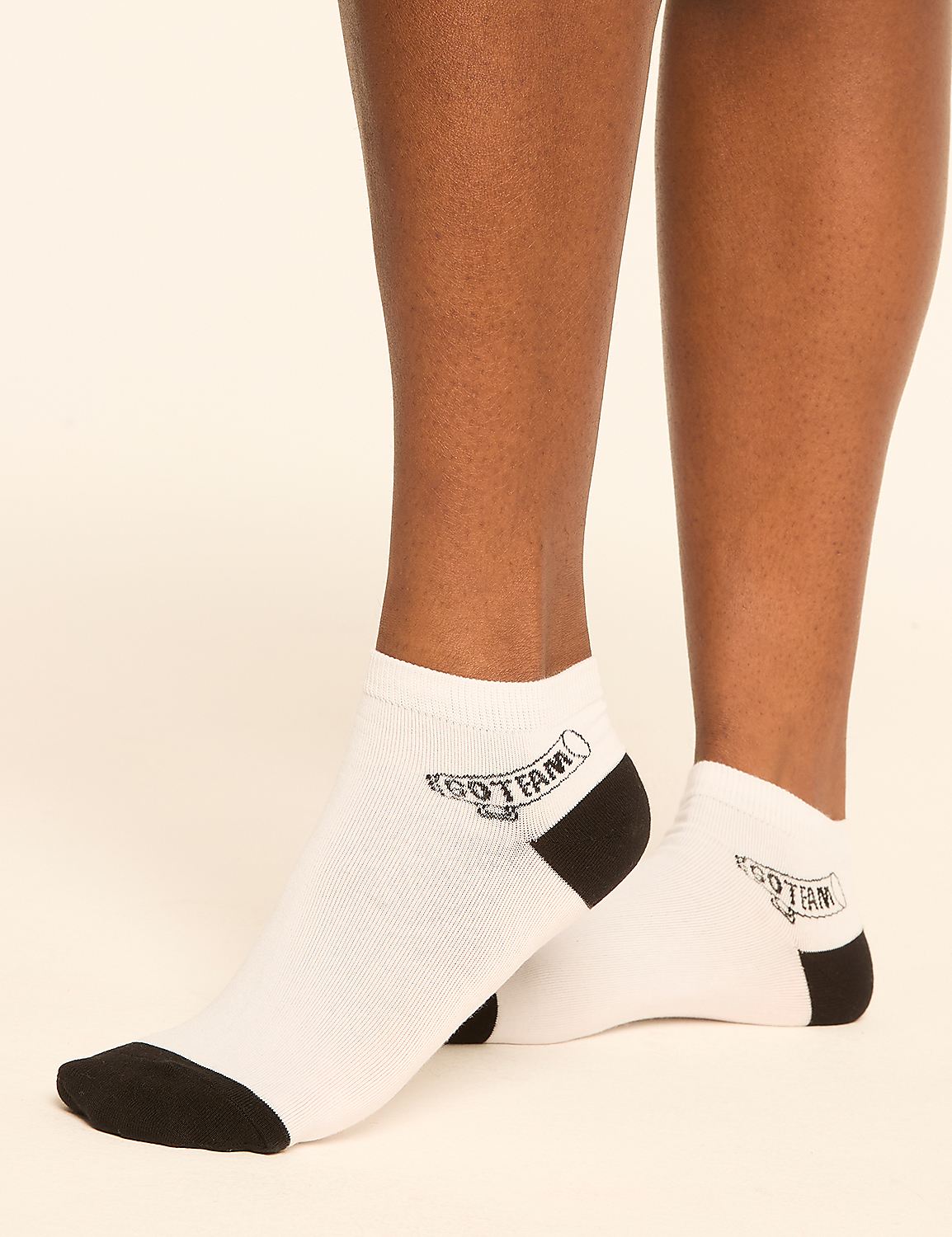 A pair of white ankle socks with black toes and heels, featuring a "KGO TEAM" logo, are worn on a person's legs against a plain, light-colored background. Product Image 3