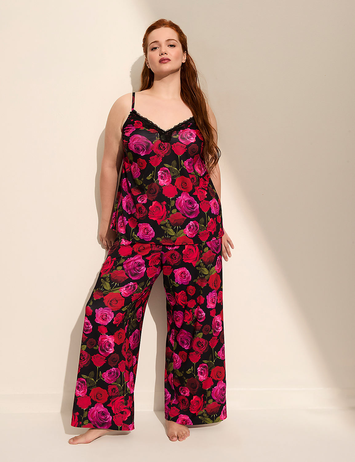 A woman with red hair stands in a floral pajama set against a plain wall with a shadow. Product Image 1