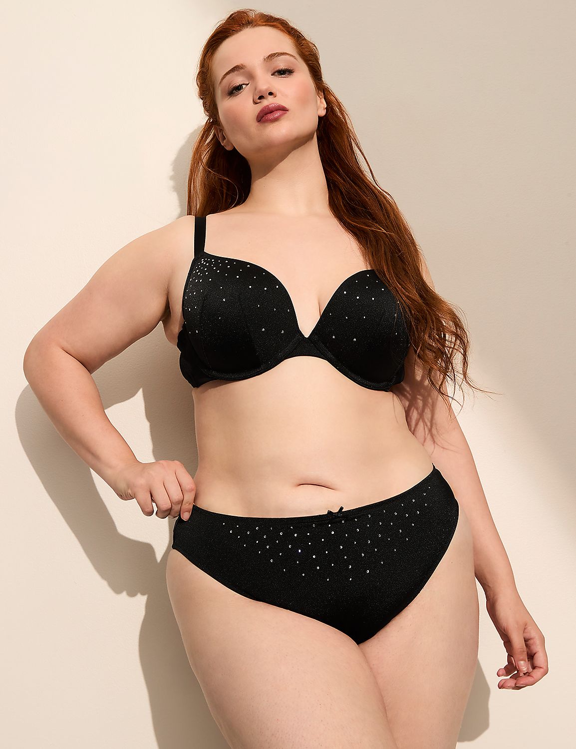 A woman with red hair poses in black lingerie against a plain, light-colored wall. Product Image 3