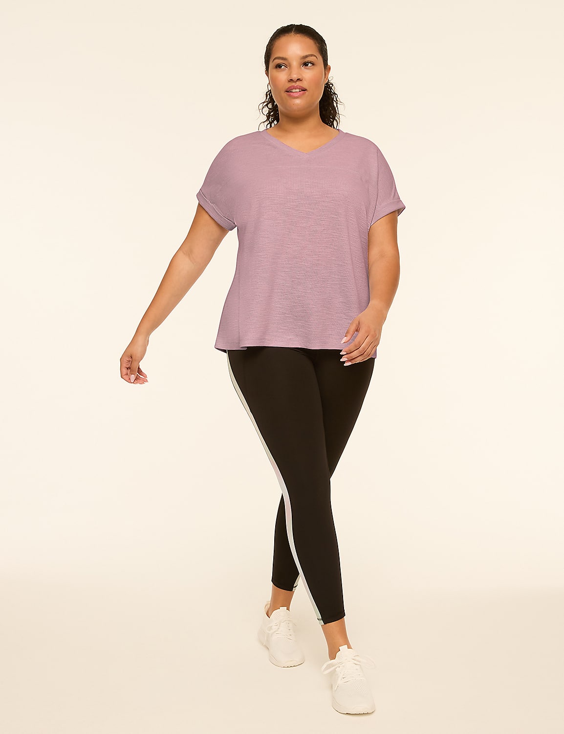 A woman in a light gray t-shirt and black leggings with a white stripe walks forward against a plain, light background. Product Image 3