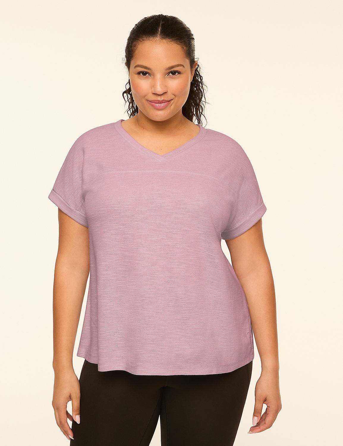 A woman with dark hair and a v-neck shirt stands against a plain, light-colored background. Product Image 1