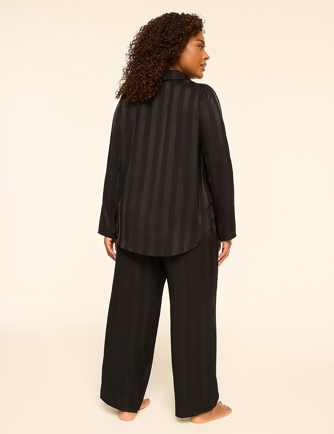 A woman stands facing away from the camera in black striped pajamas against a plain, light-colored background. Product Image 2