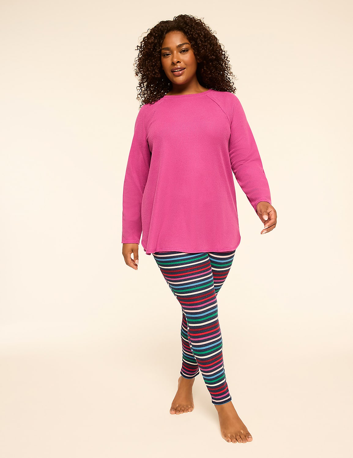 A woman in a pink tunic and striped leggings stands against a plain, light-colored background. Product Image 1