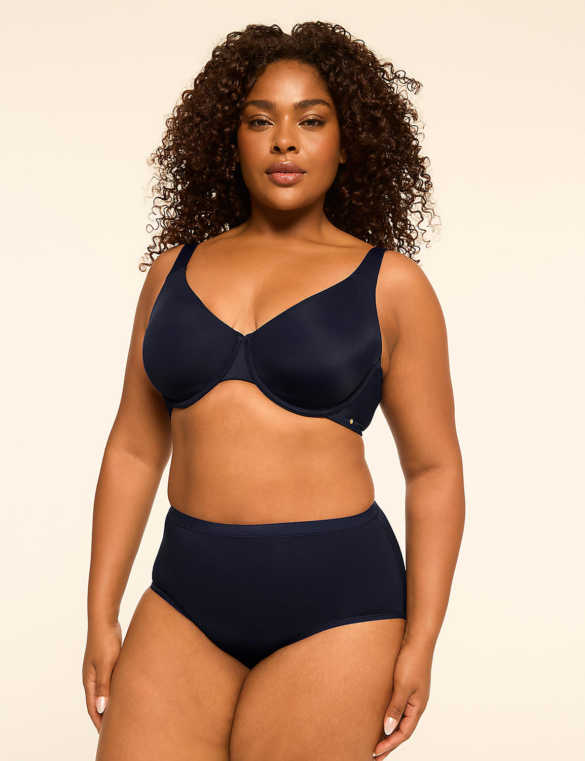 A woman with curly dark hair poses in a navy blue bra and high-waisted underwear against a plain, light-colored background. Product Image 4